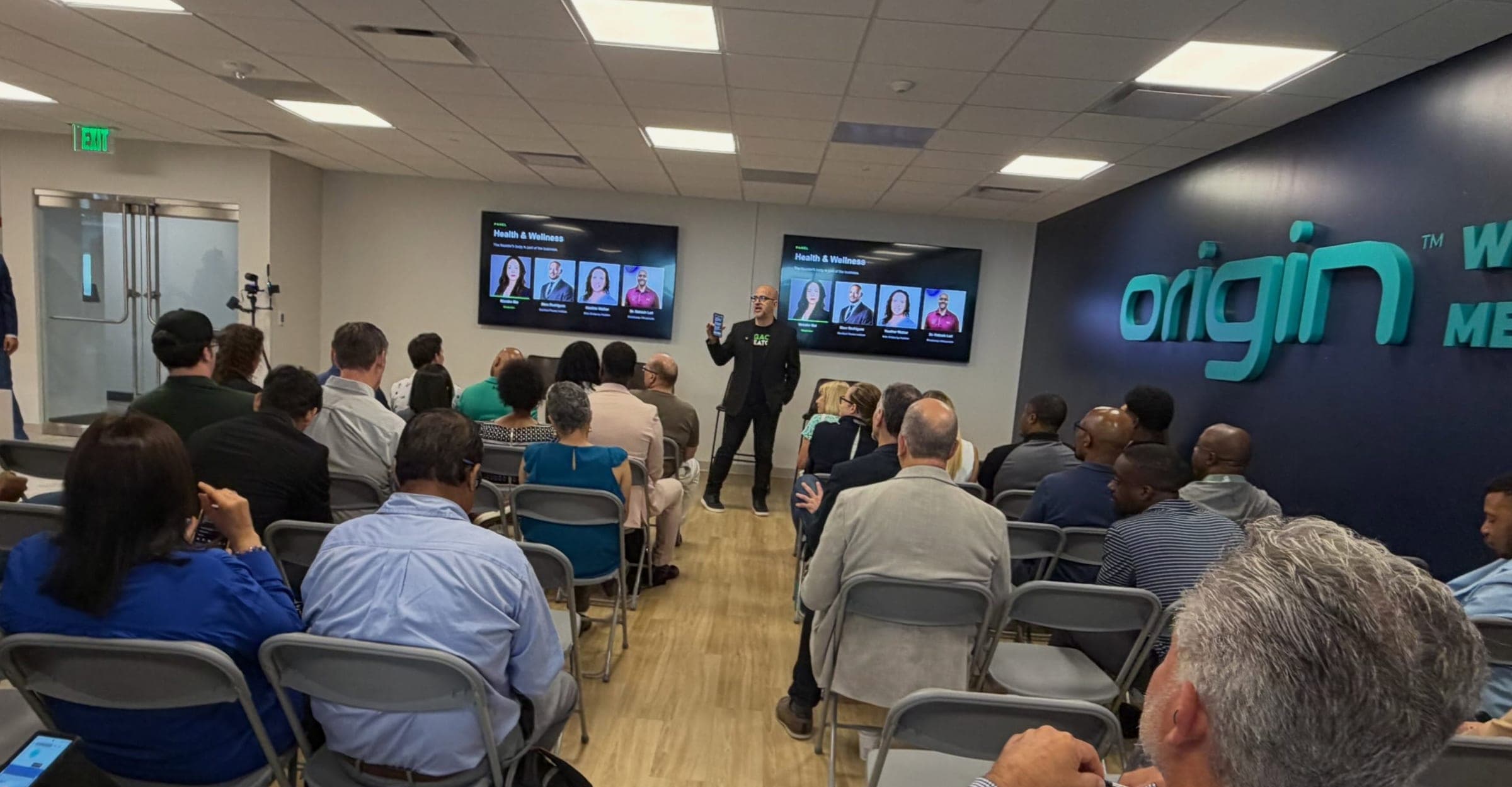 A full room of founders at Legacy Creators inside Plug and Play Frisco, watching the Health and Wellness panel introduction.